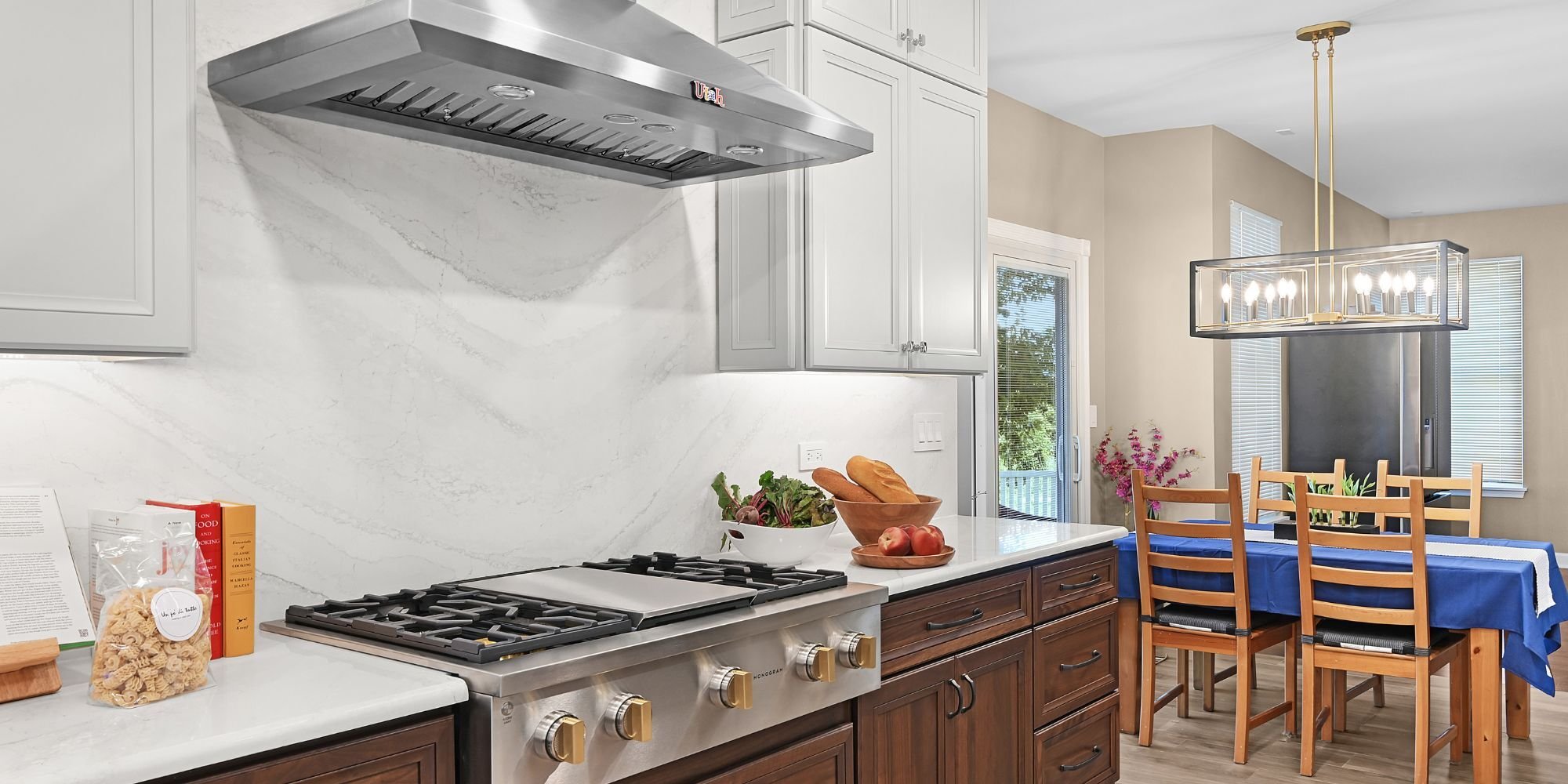 Kitchen remodel in Aurora, IL featuring a stainless steel gas range, hood vent, and a dining table with a custom chandelier by J&J Construction.