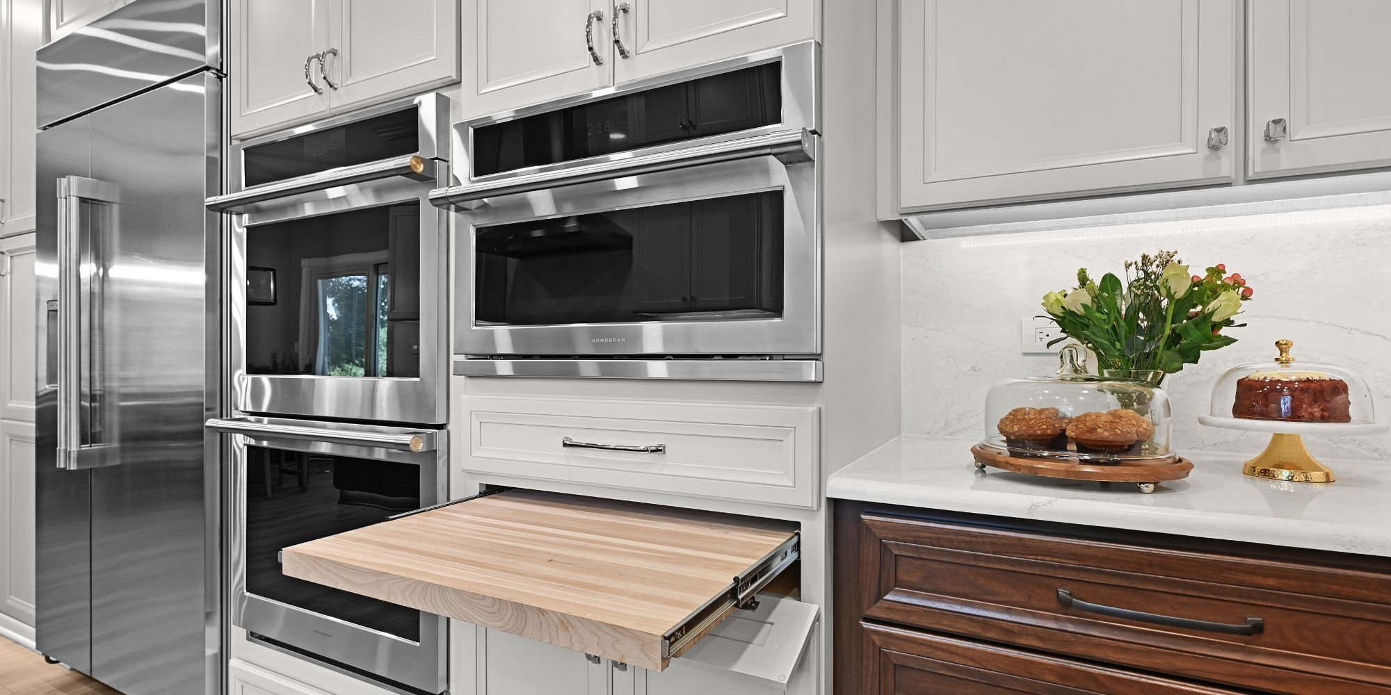 Kitchen remodel in Aurora, IL with a new stainless steel double oven and matching microwave with a slide-out cutting board underneath by J&J Constructi