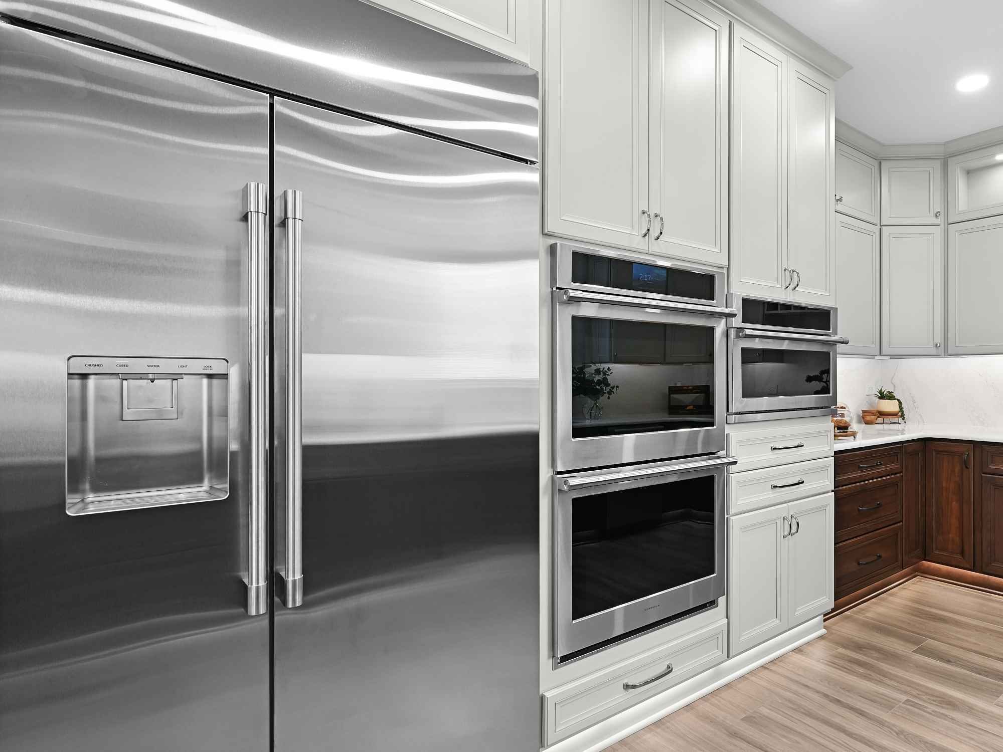 New high-end stainless steel Monogram refrigerator, double oven, and microwave in an Aurora, IL kitchen remodel by J&J Construction.