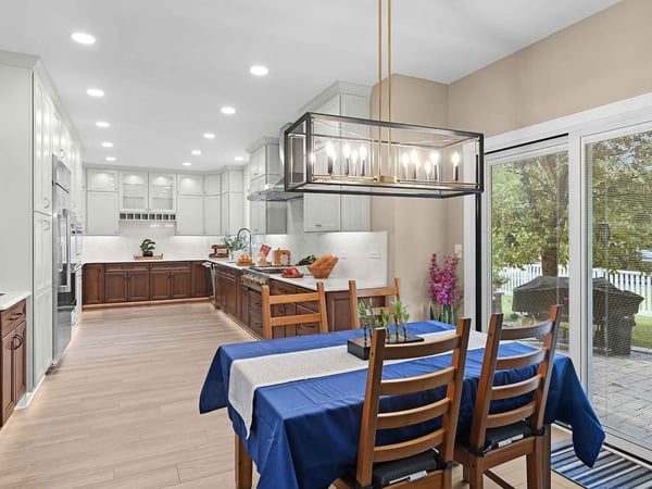 Photo of a remodeled eat-in kitchen with recessed lighting and a chandelier above the dining table that overlooks a patio through the sliding glass door by J&J C