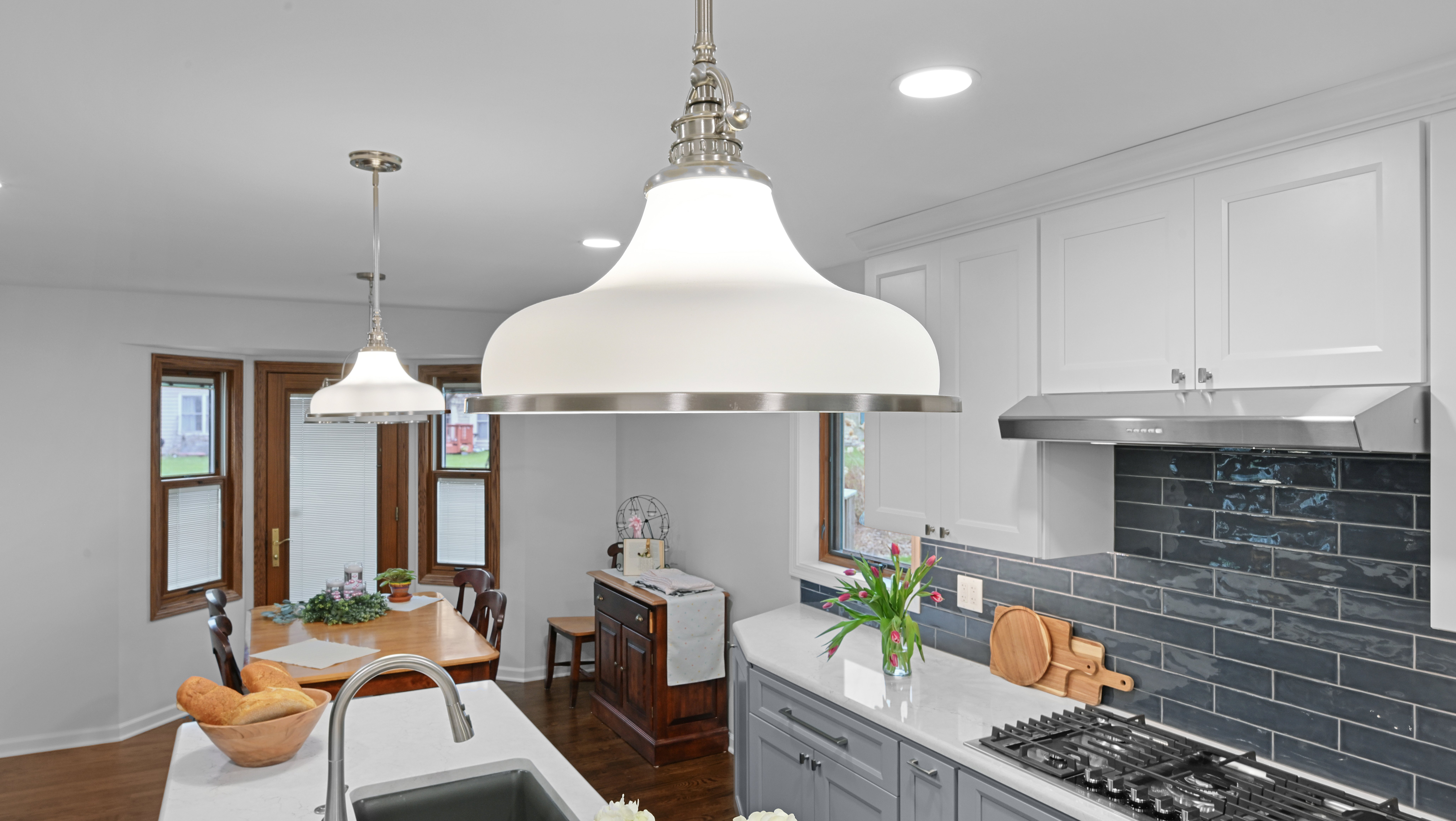 A kitchen remodel featuring a sink island, gas cooktop, and Quoizel pendant lights in Naperville, IL.