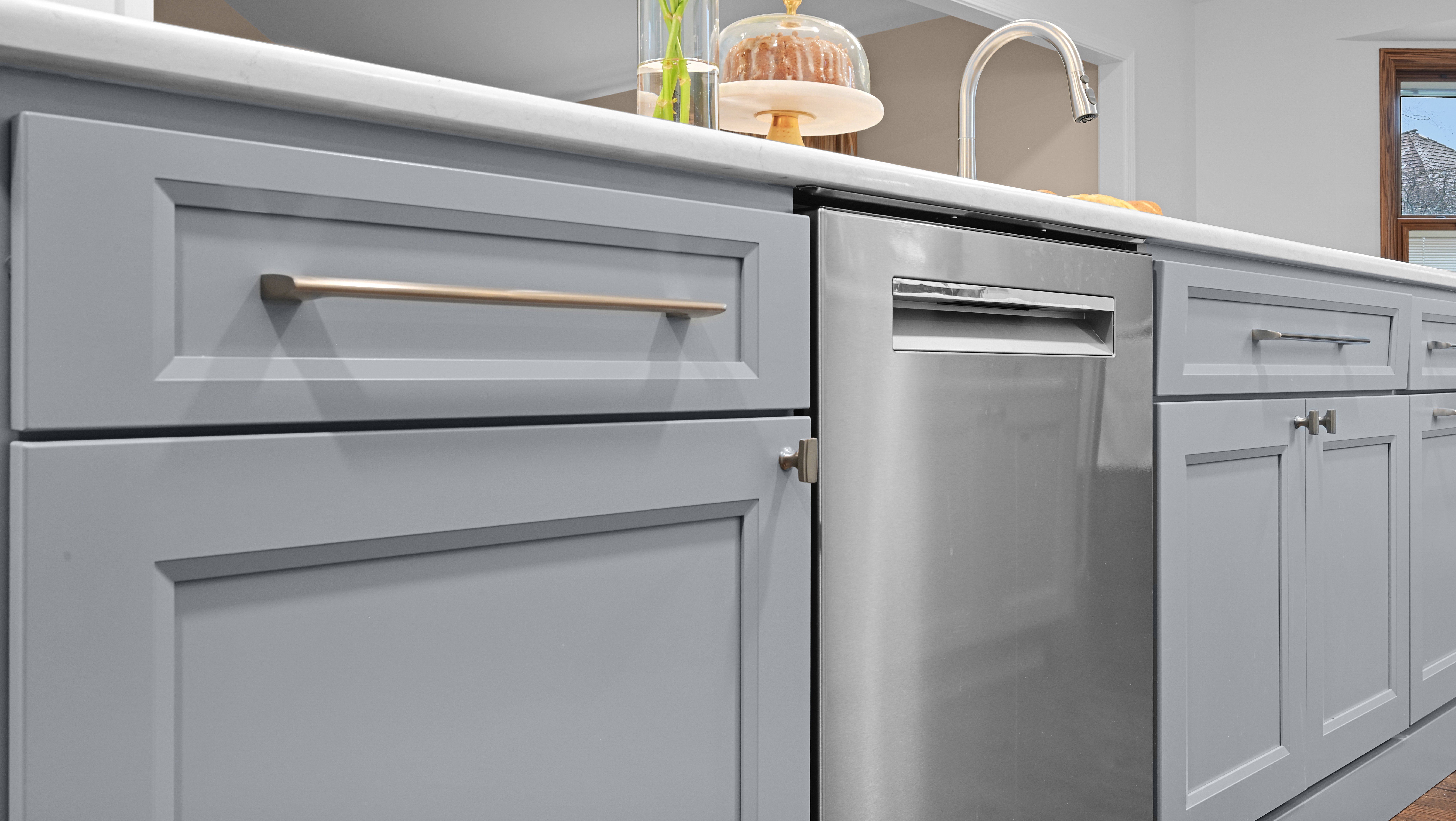 A kitchen remodel by J&J Construction featuring soft gray cabinets with satin nickel hardware and a stainless dishwasher in Naperville, IL