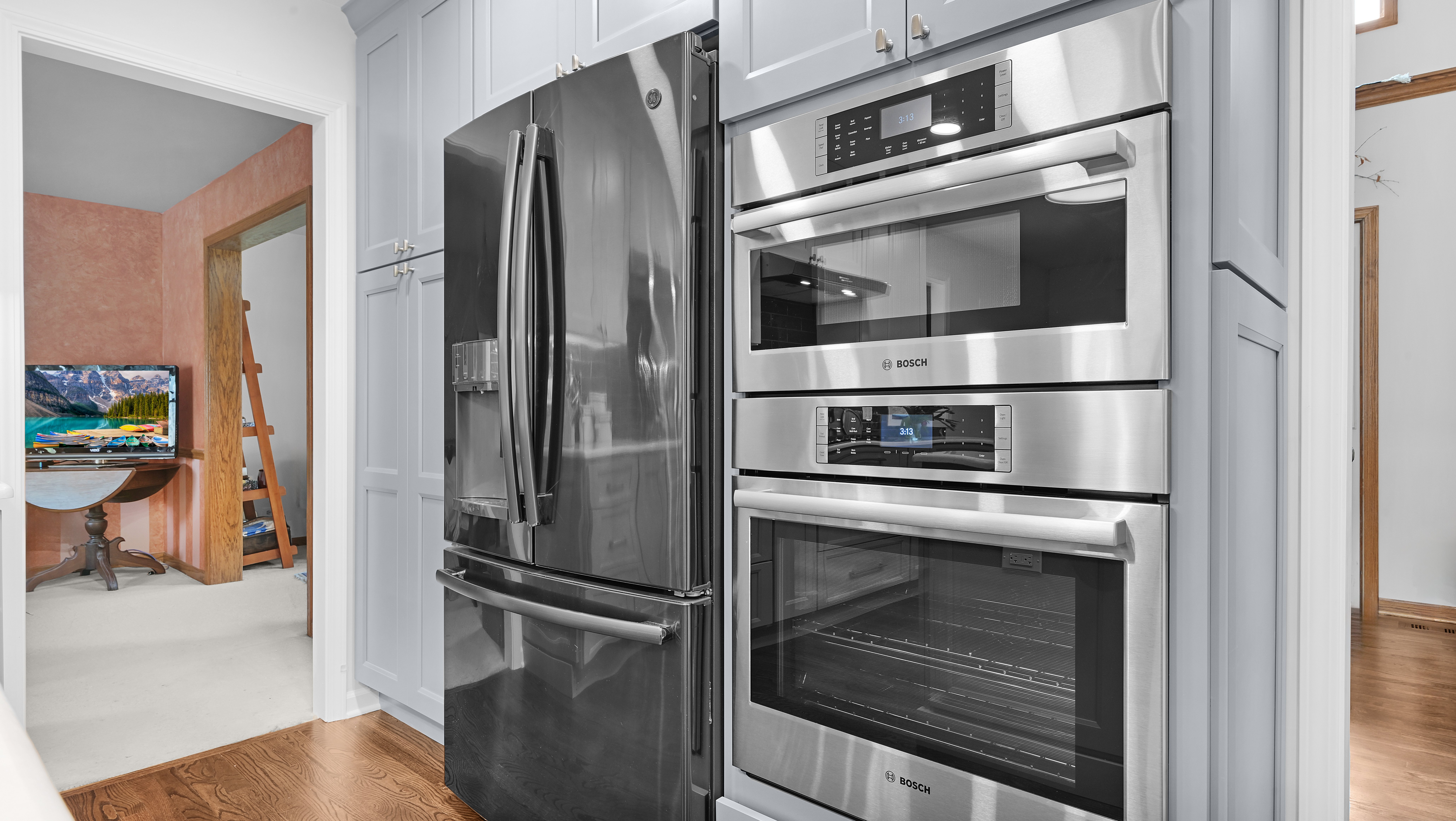 A remodeled kitchen featuring an existing French-door refrigerator and new stainless double oven by J&amp;J Construction.