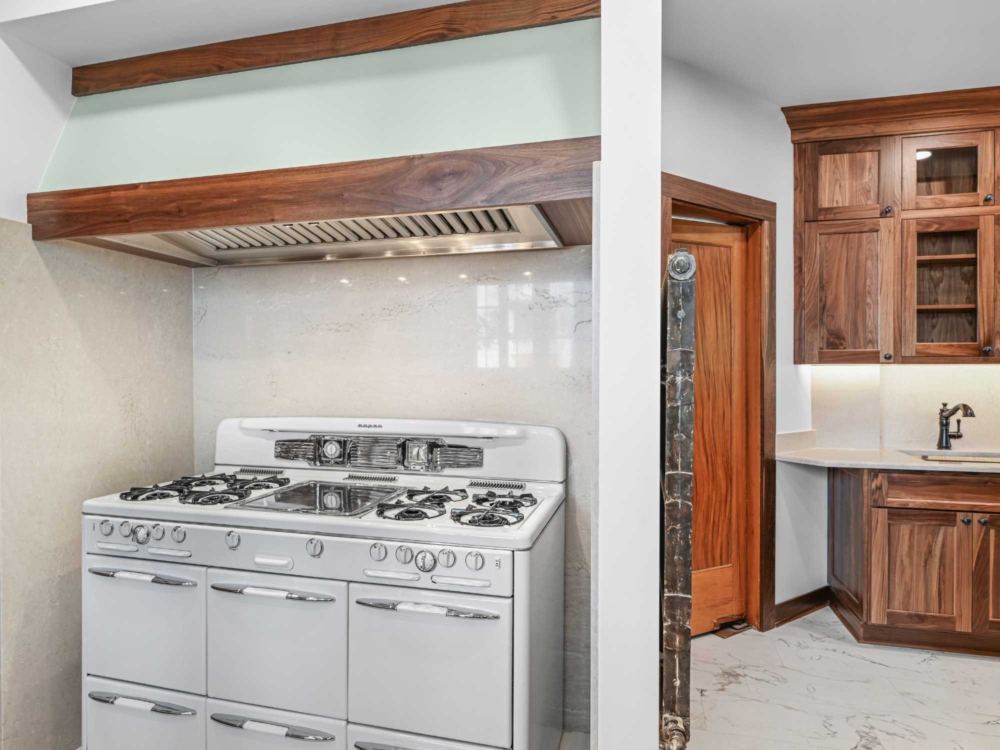 Image of a refinished vintage stove, bertch cabinets, and quartz backsplash in a kitchen remodel by J&J Construction
