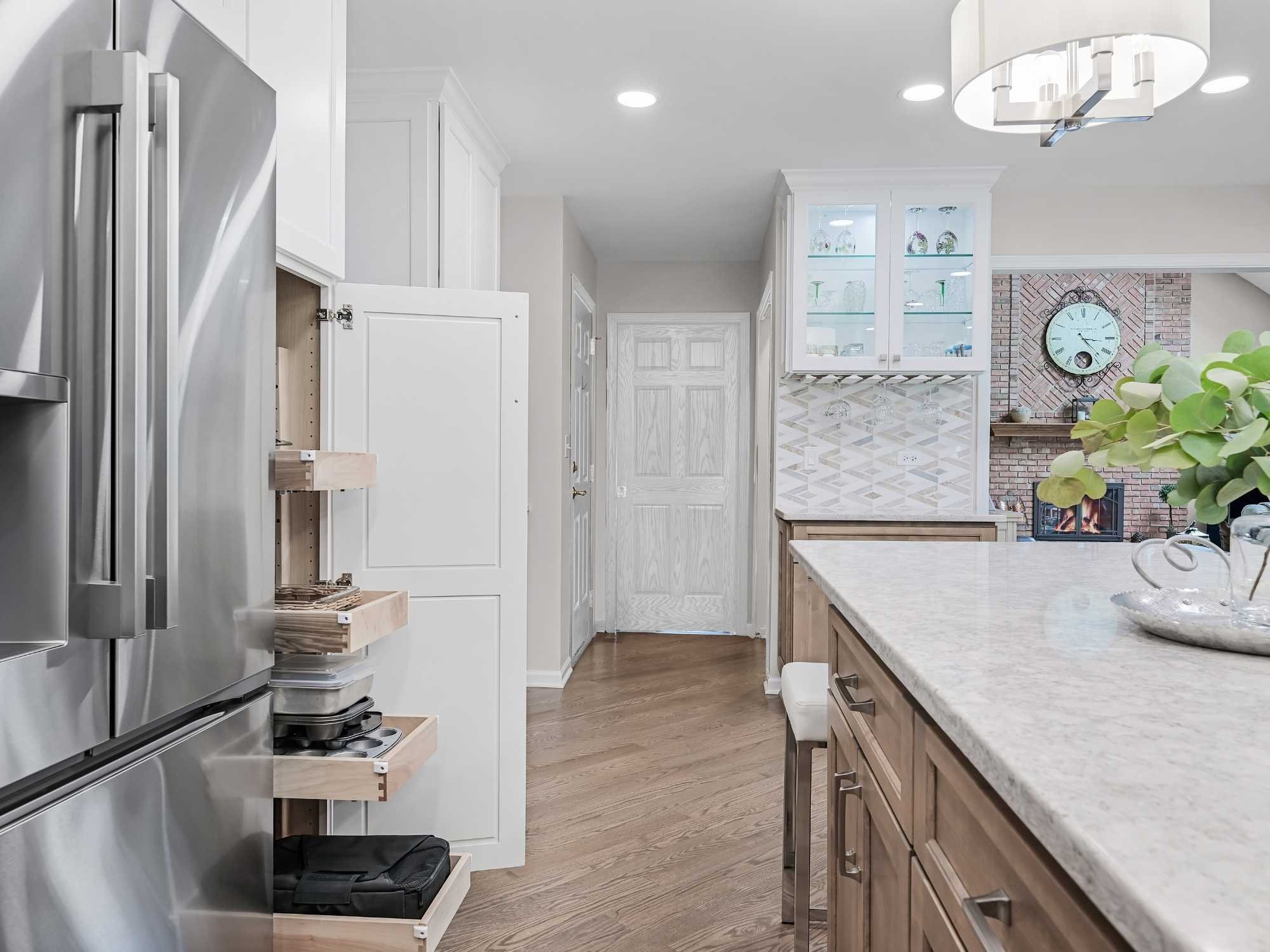 Image of kitchen remodel in Naperville, IL featuring hidden storage drawers, glass cabinets and large island by J and J Construction