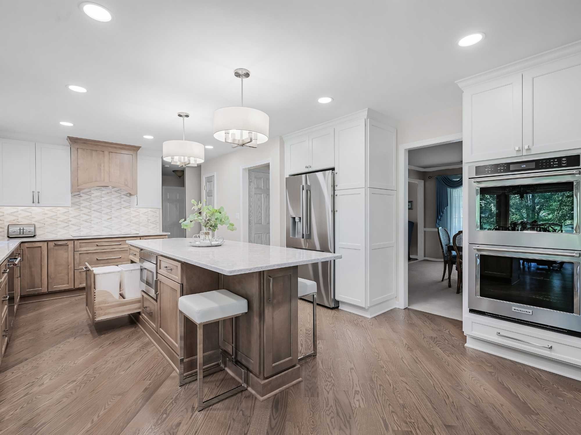 Image of kitchen remodel in Naperville, IL featuring open layout, wood island, white cabinets and modern lighting by J and J Construction